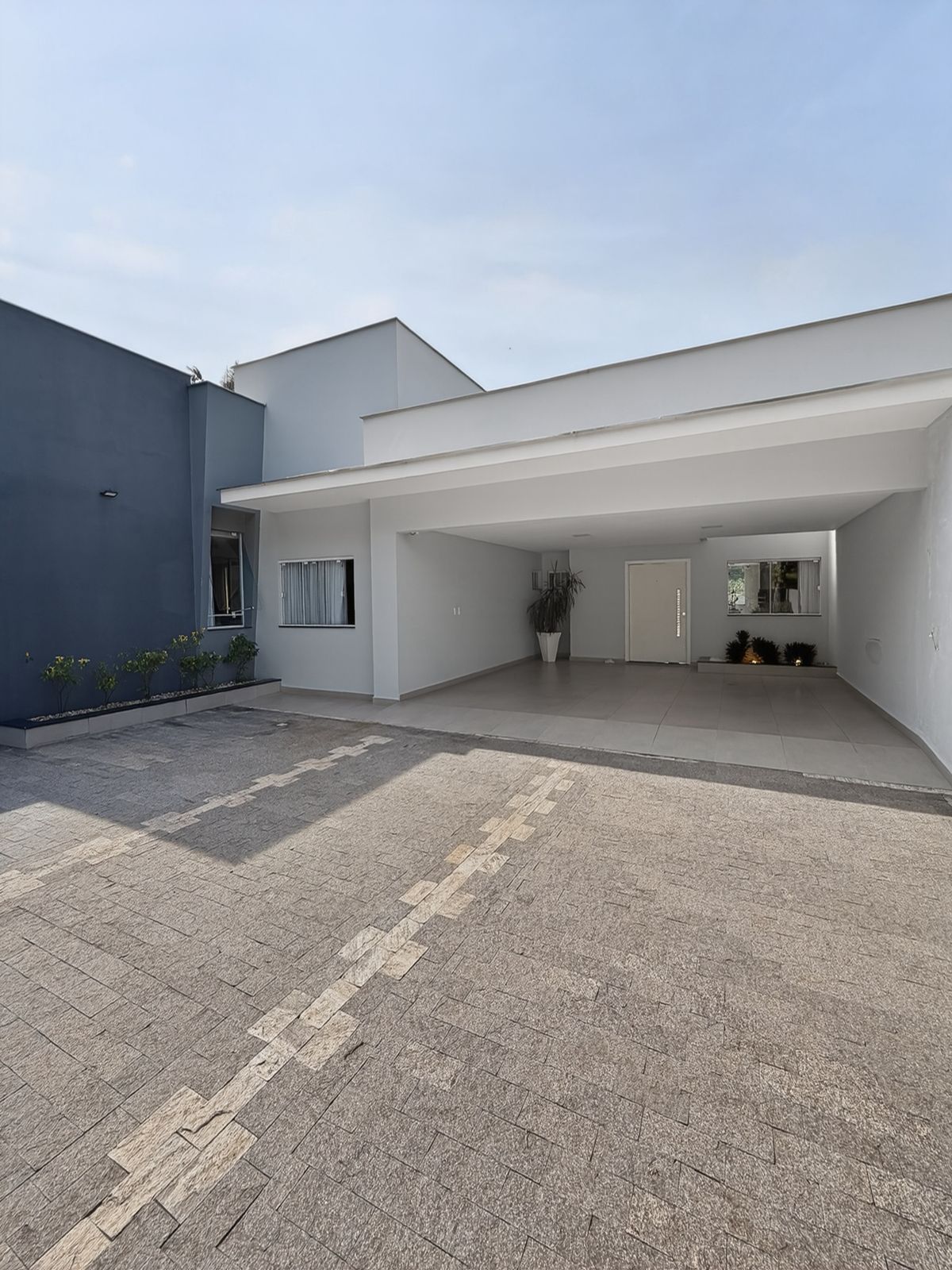 Entrada principal da casa com garagem coberta e fachada branca e cinza