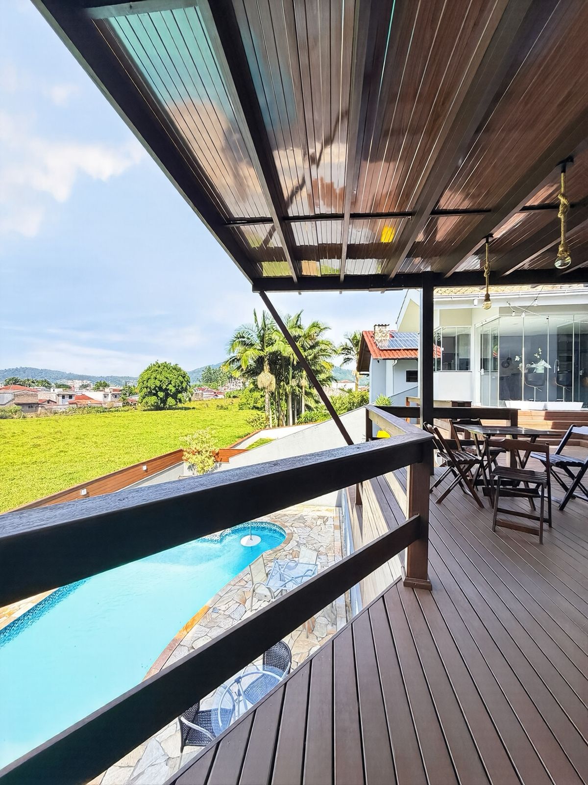 Vista da varanda da área de festas para o vale verde e a piscina lá embaixo