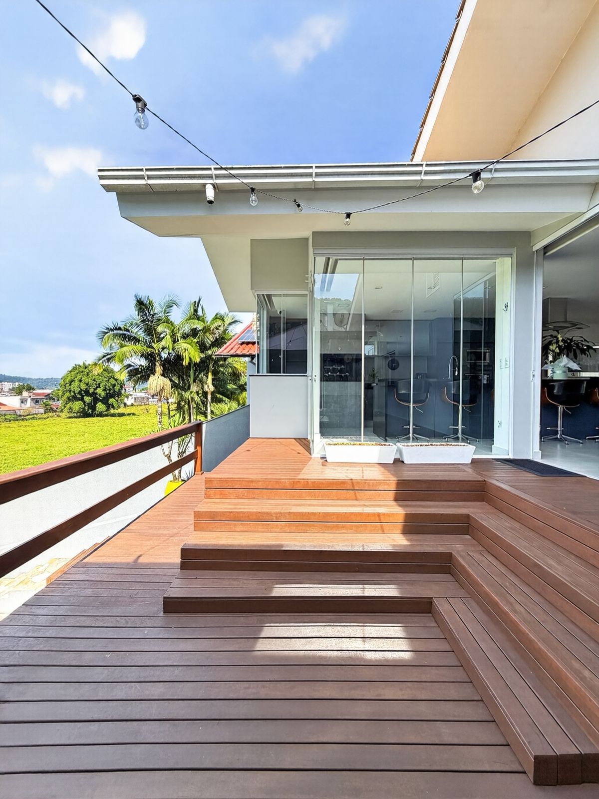 Deck superior de madeira com vista para o vale e acesso à casa pelos degraus
