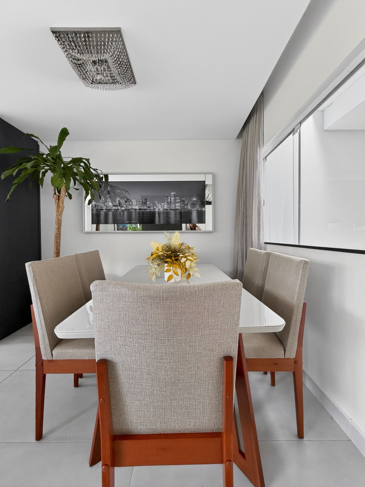 Sala de jantar com lustre de cristal, mesa para seis lugares e cortina